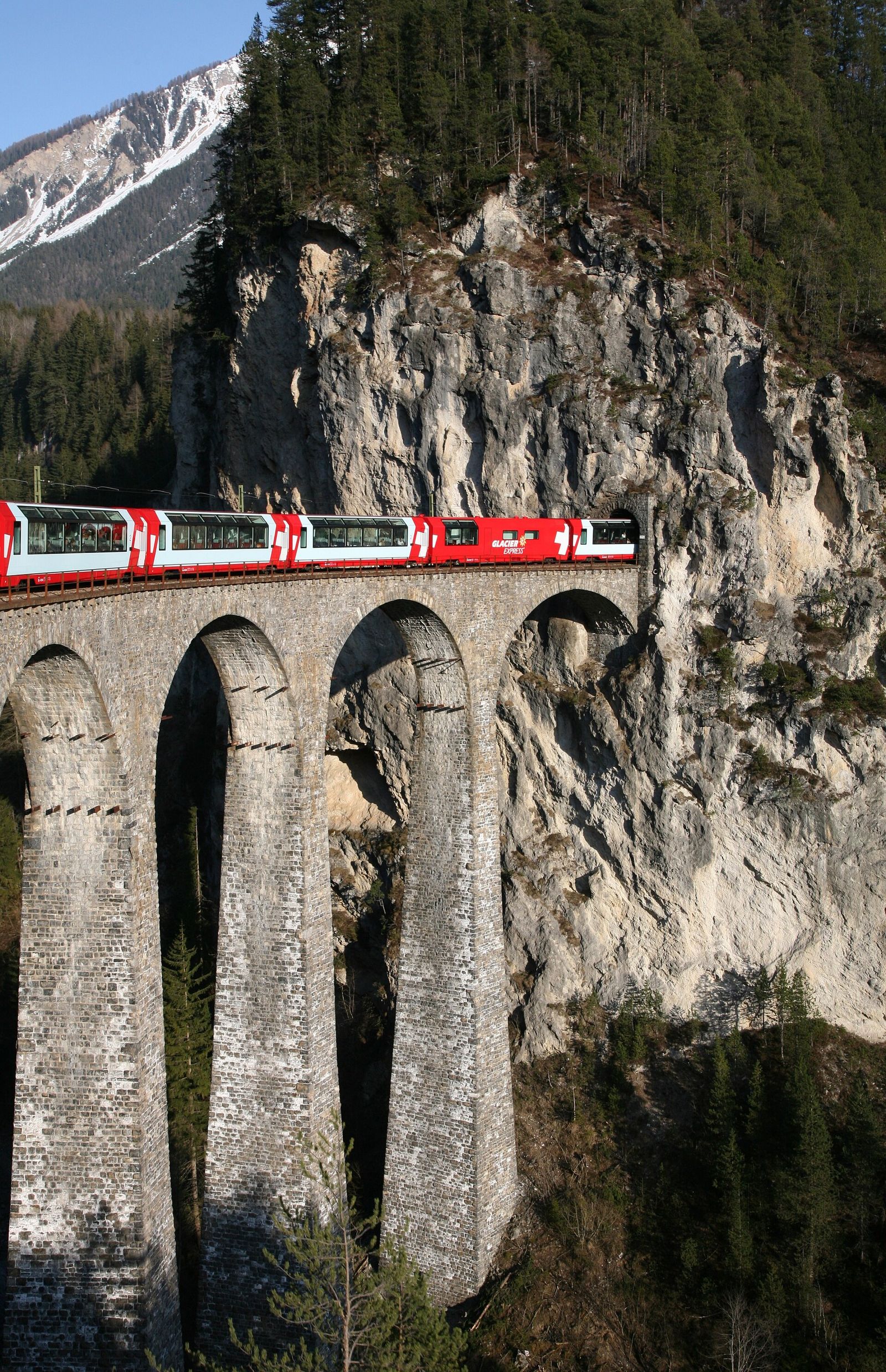 A train crossing a stone viaduct in the Swiss Alps